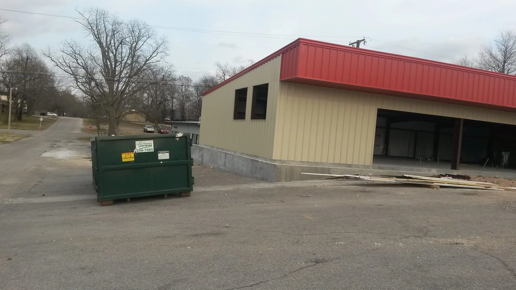 Metal-sided building under construction with a red canopy and open bays