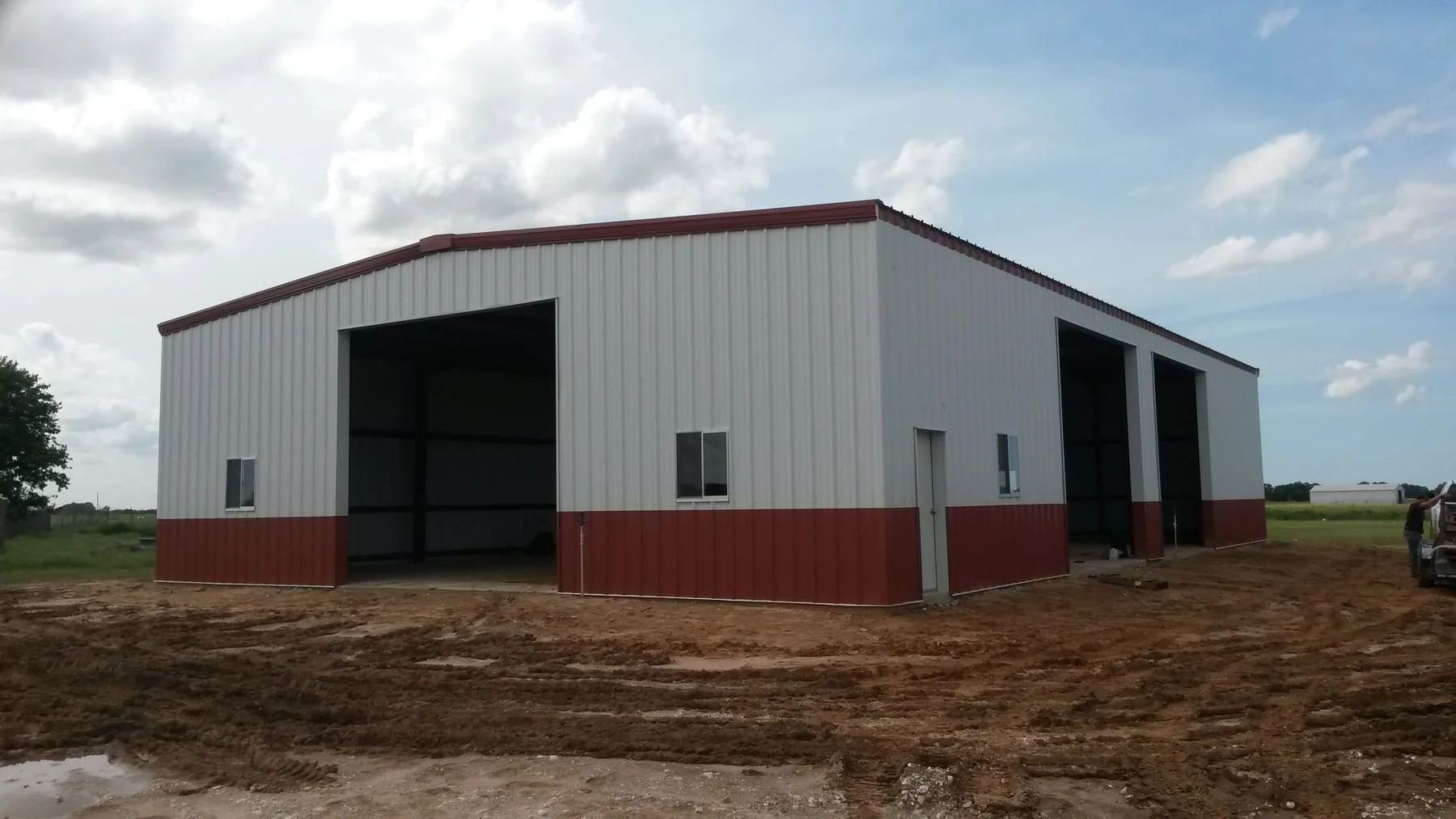 White and red metal building with several large open bays