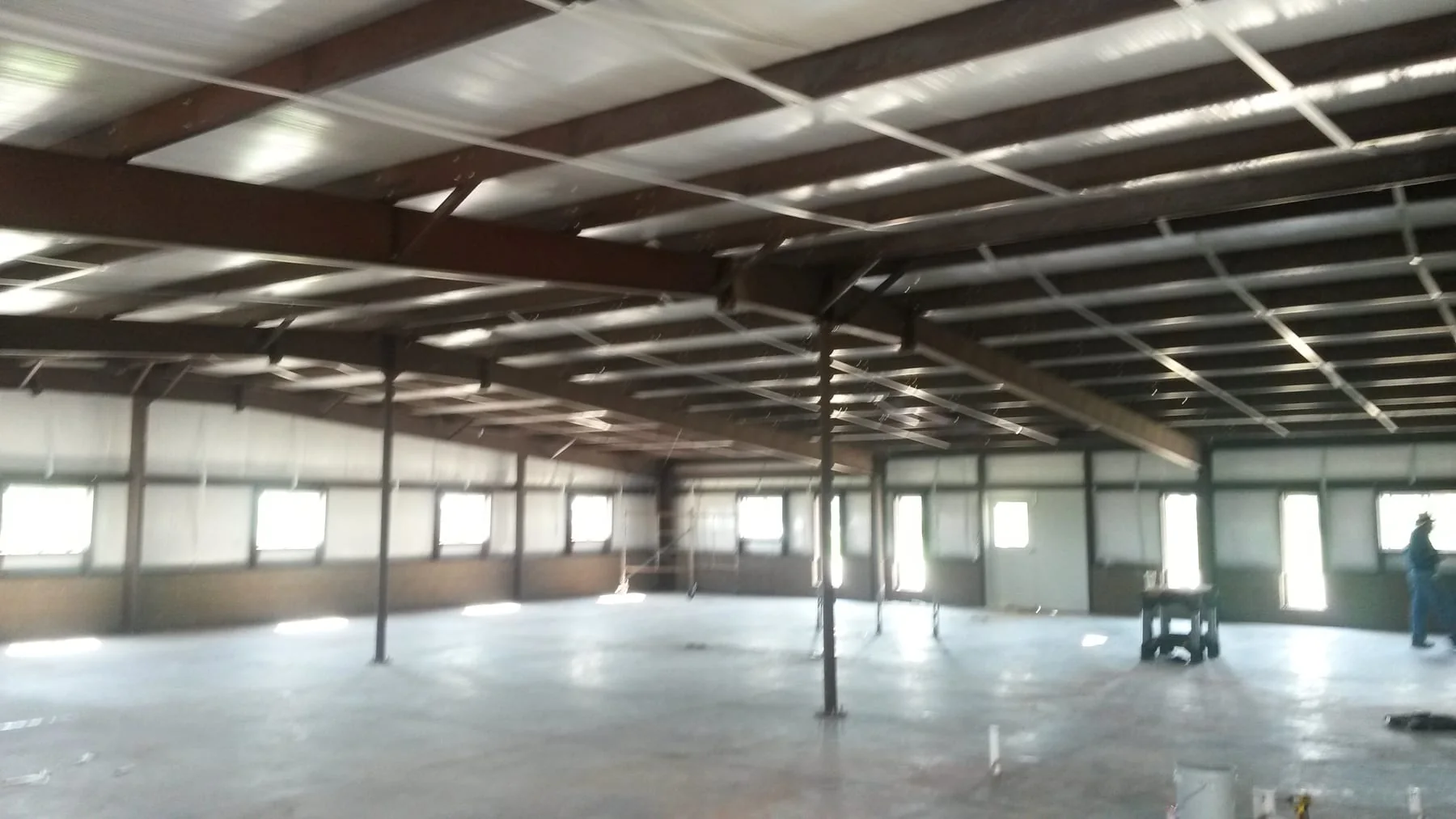 Open interior of a metal building with exposed steel roof framing and concrete floor
