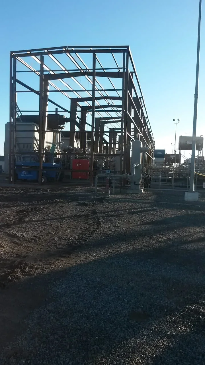 Tall steel frame erected around industrial piping and equipment