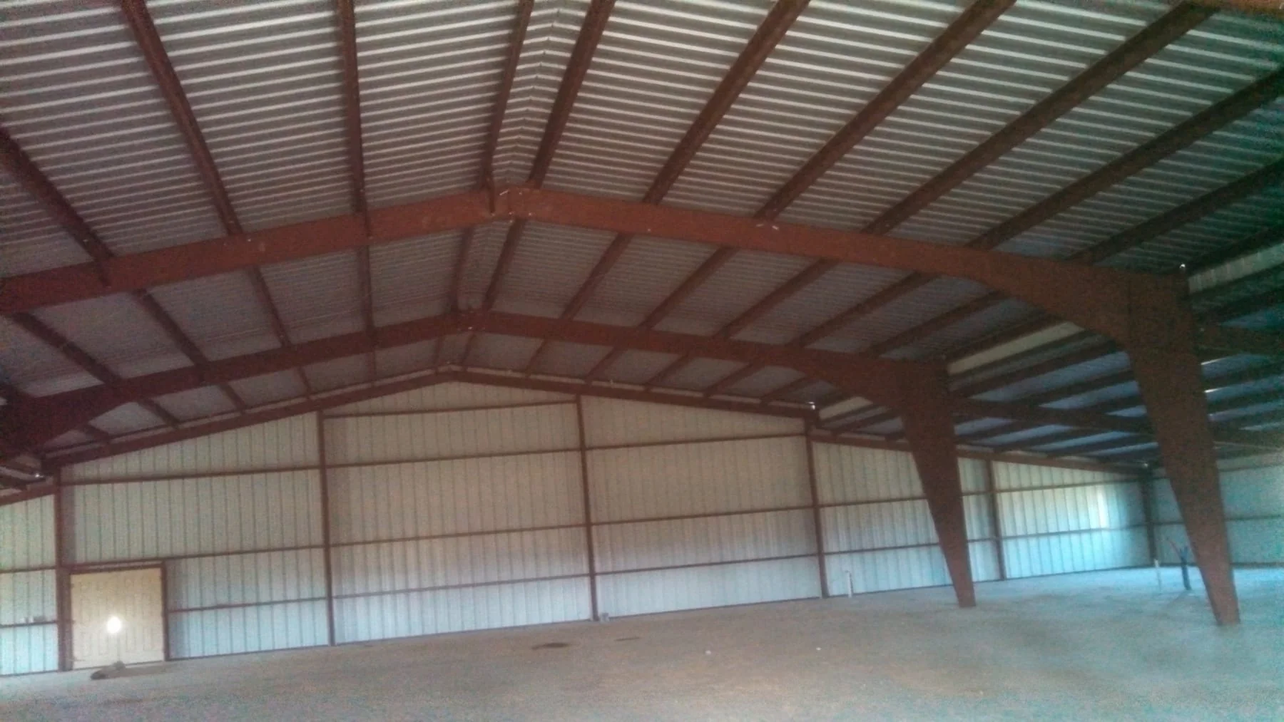 Interior of a metal building with exposed red steel framing and roof panels
