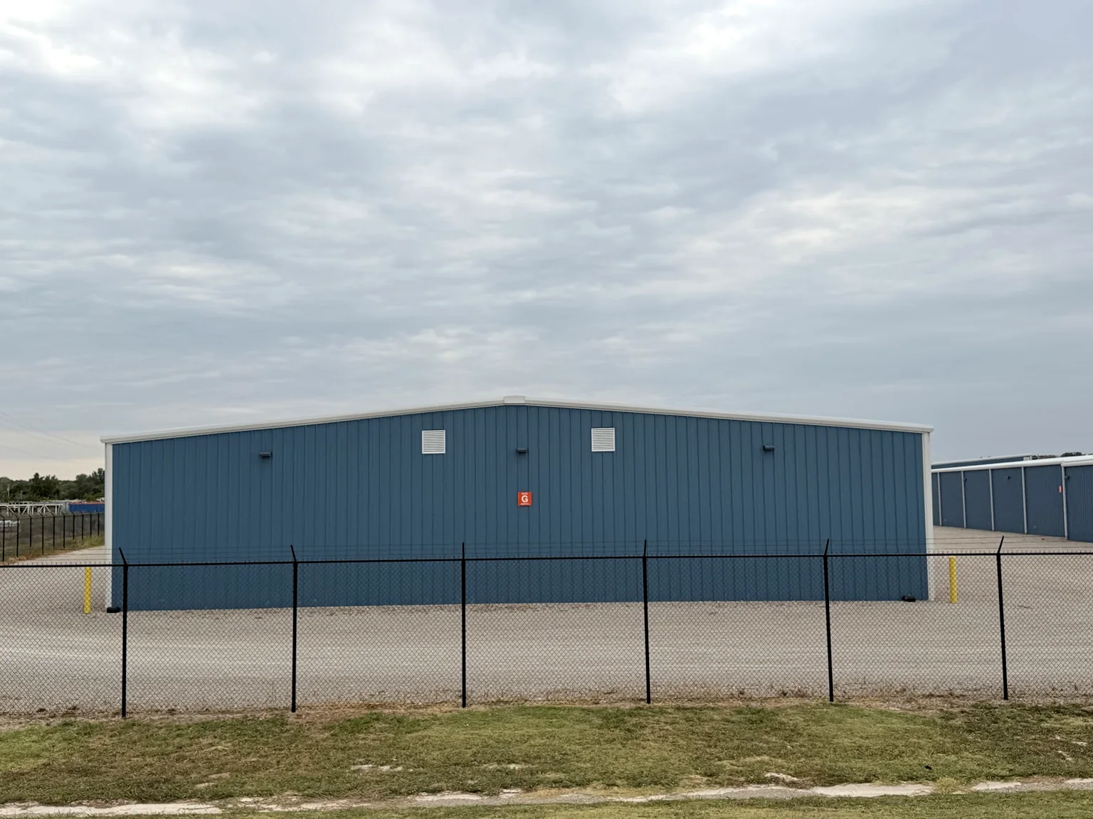 Completed blue metal storage building viewed across the fenced Norman South facility