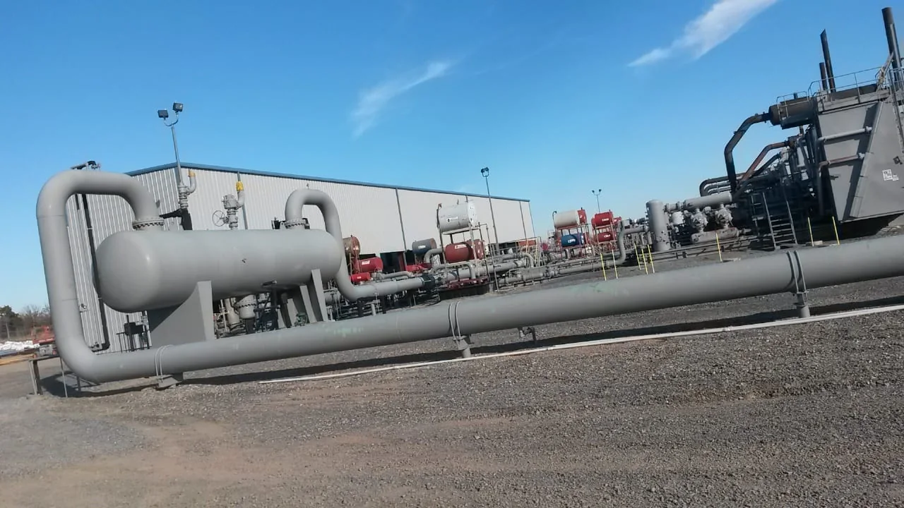 Industrial piping, tanks and equipment beside a metal-sided enclosure