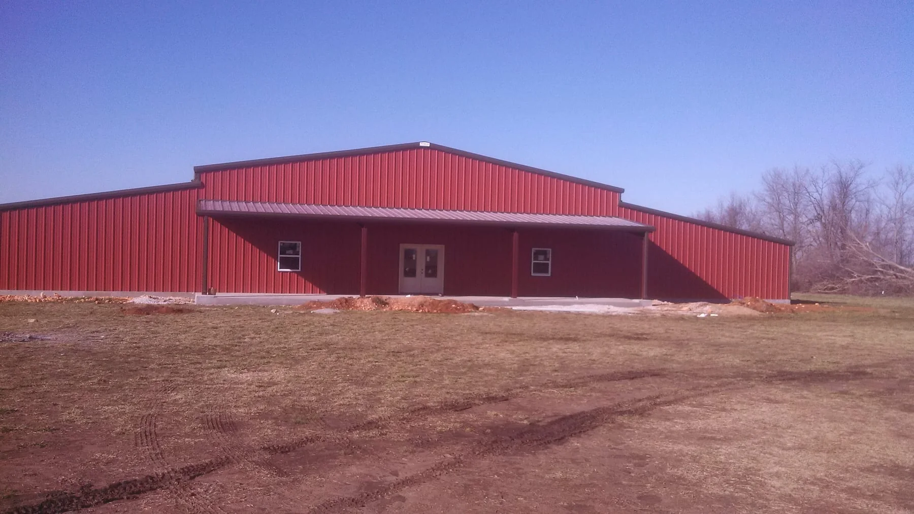 Front view of a red metal building with a covered entrance and double doors