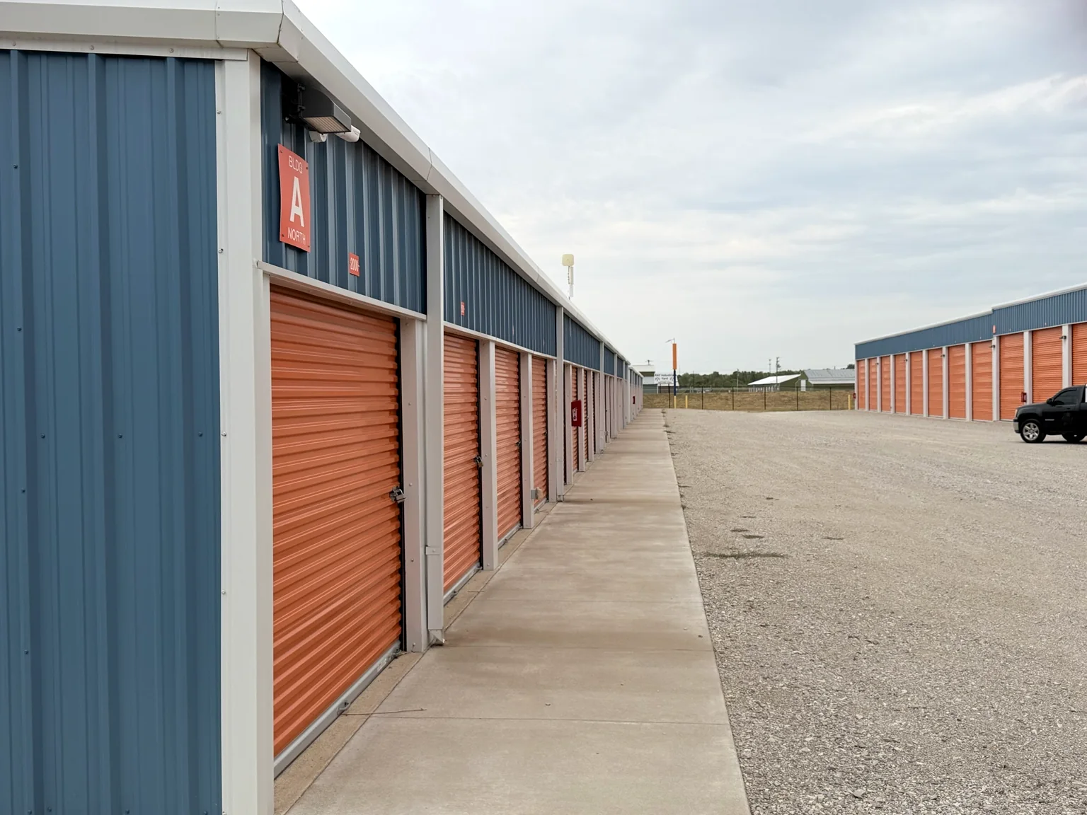 Long storage-building aisle with blue metal walls and orange roll-up doors
