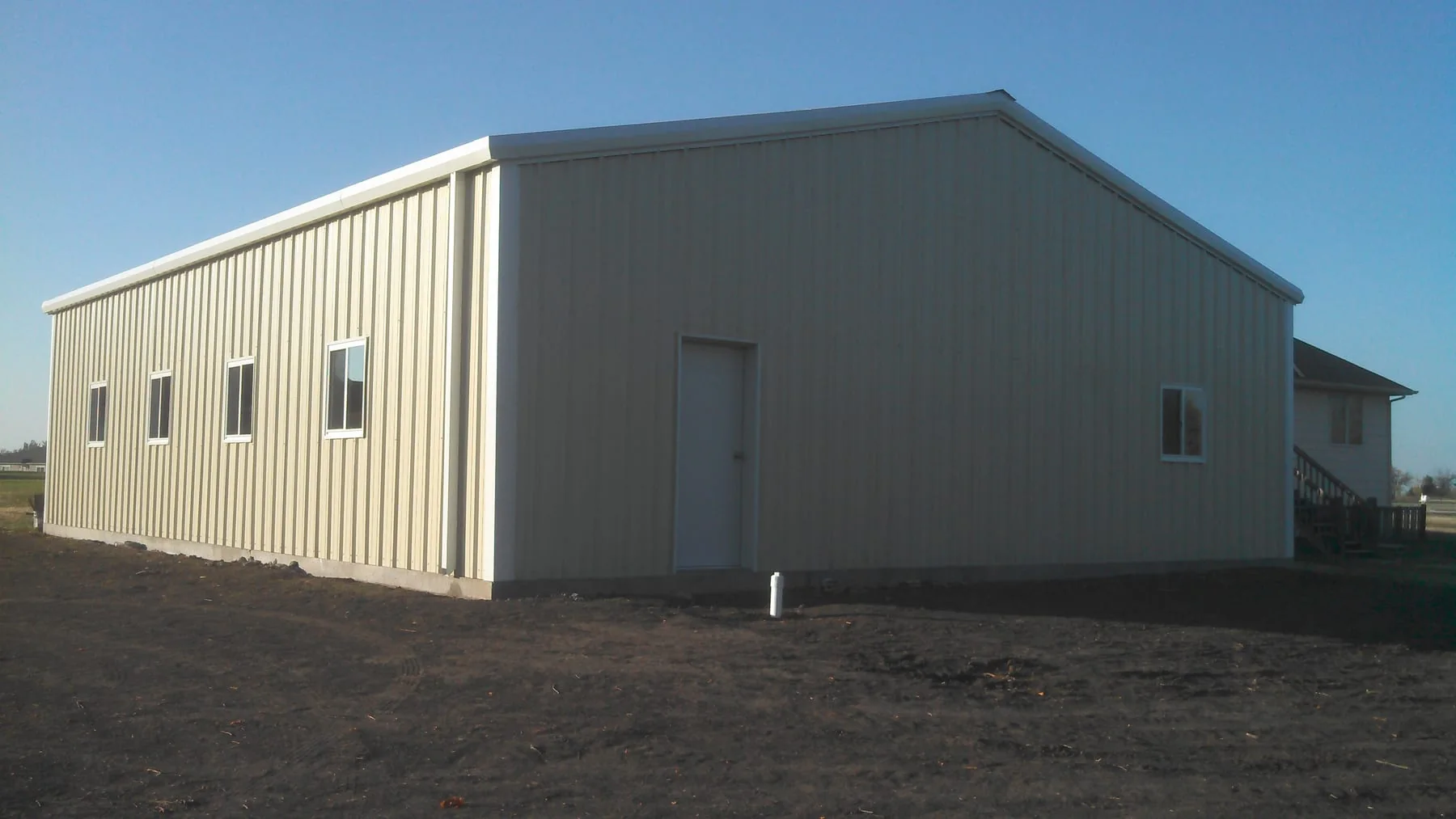 Finished light-colored metal building with windows and a walk door