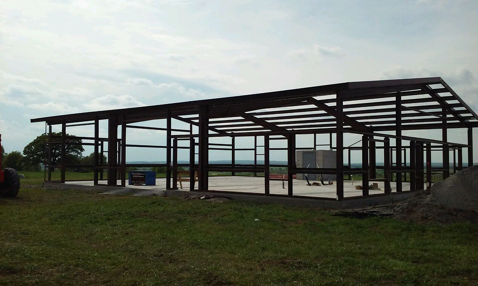 Wide side view of a red-iron building frame under construction