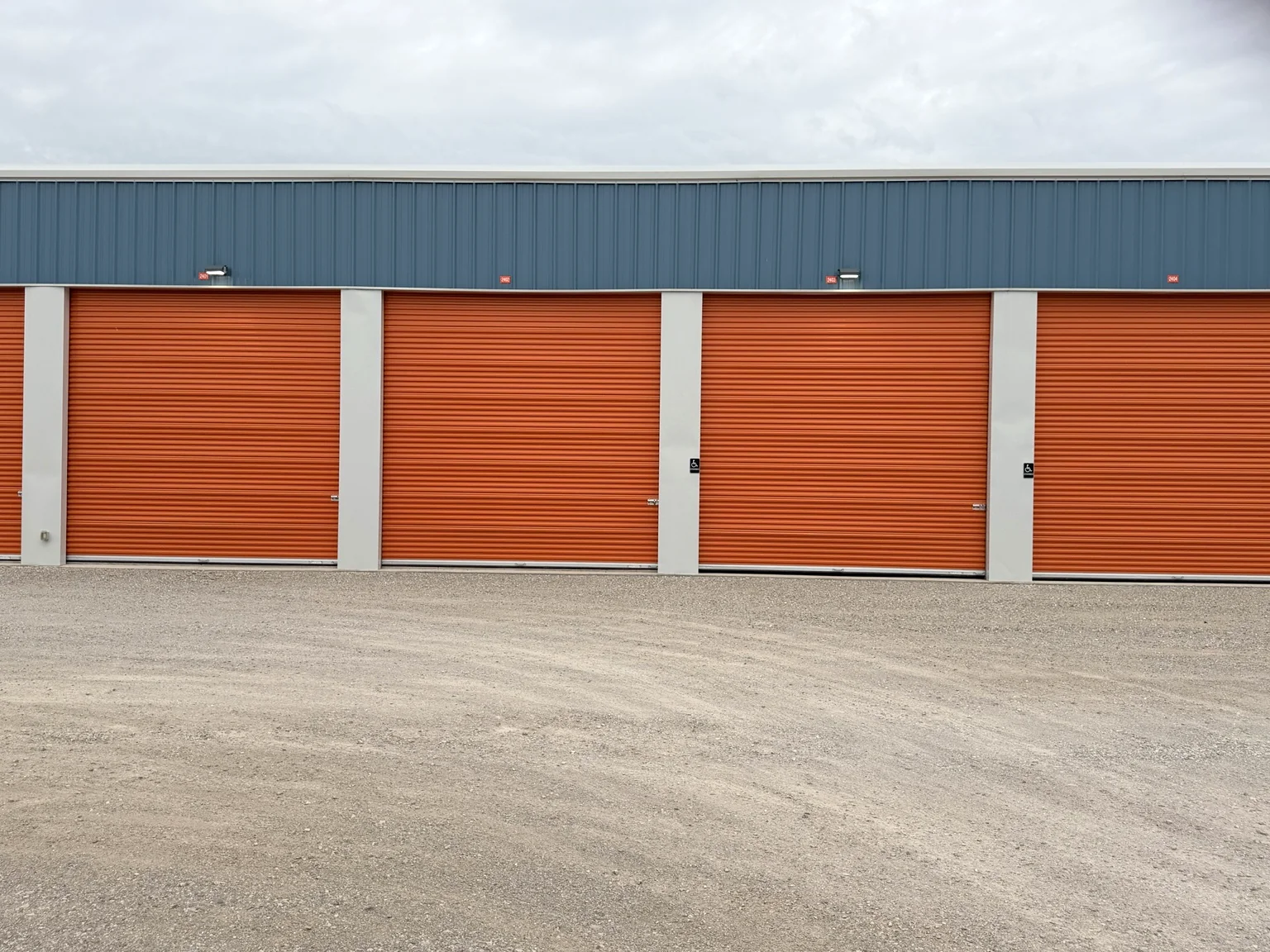 Row of orange roll-up storage doors beneath blue metal wall panels