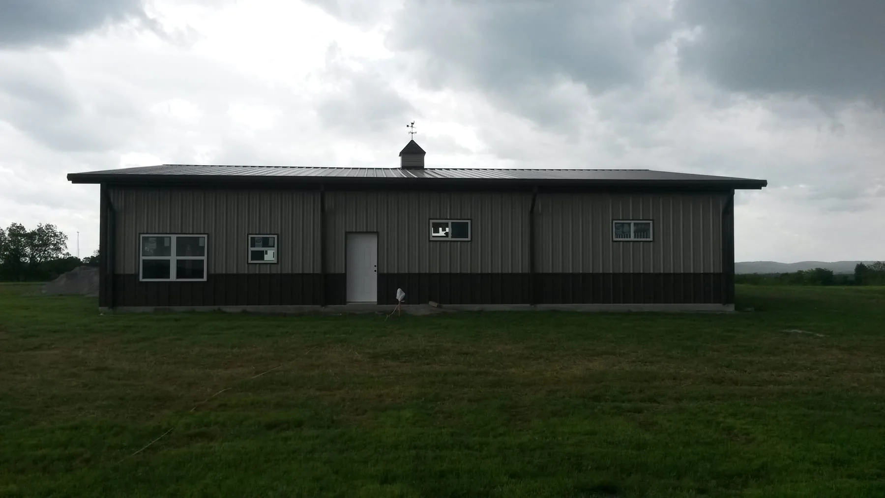 Side elevation of a finished gray metal building with windows and a white door