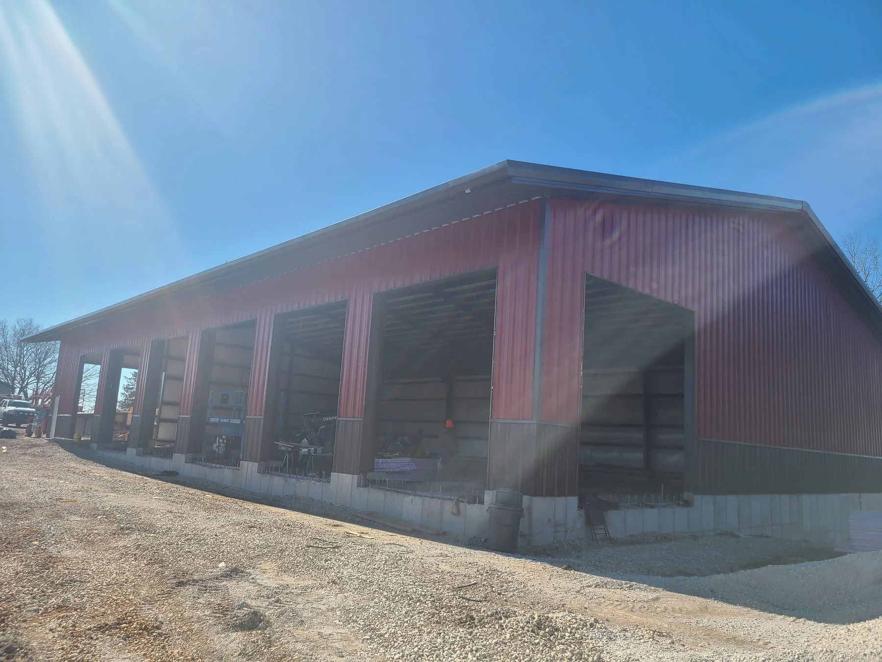Red metal-sided building with several tall open bays