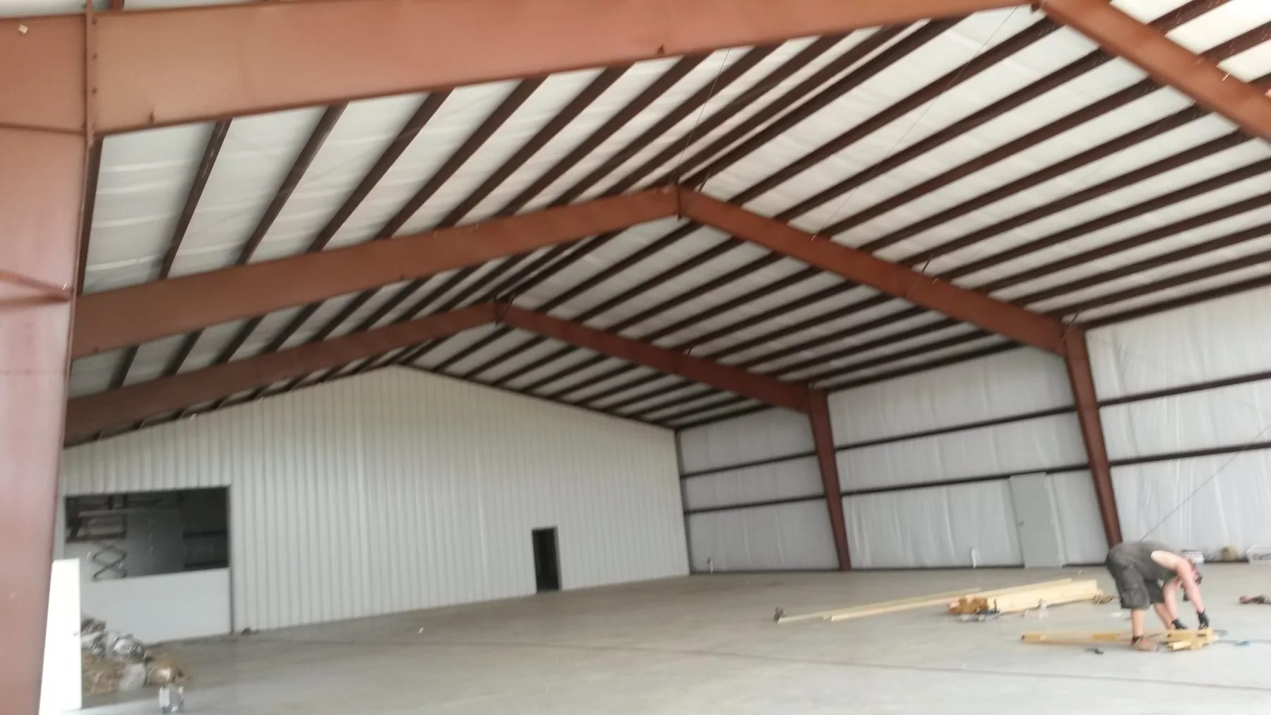 Metal building interior with exposed red steel framing and white wall and roof panels