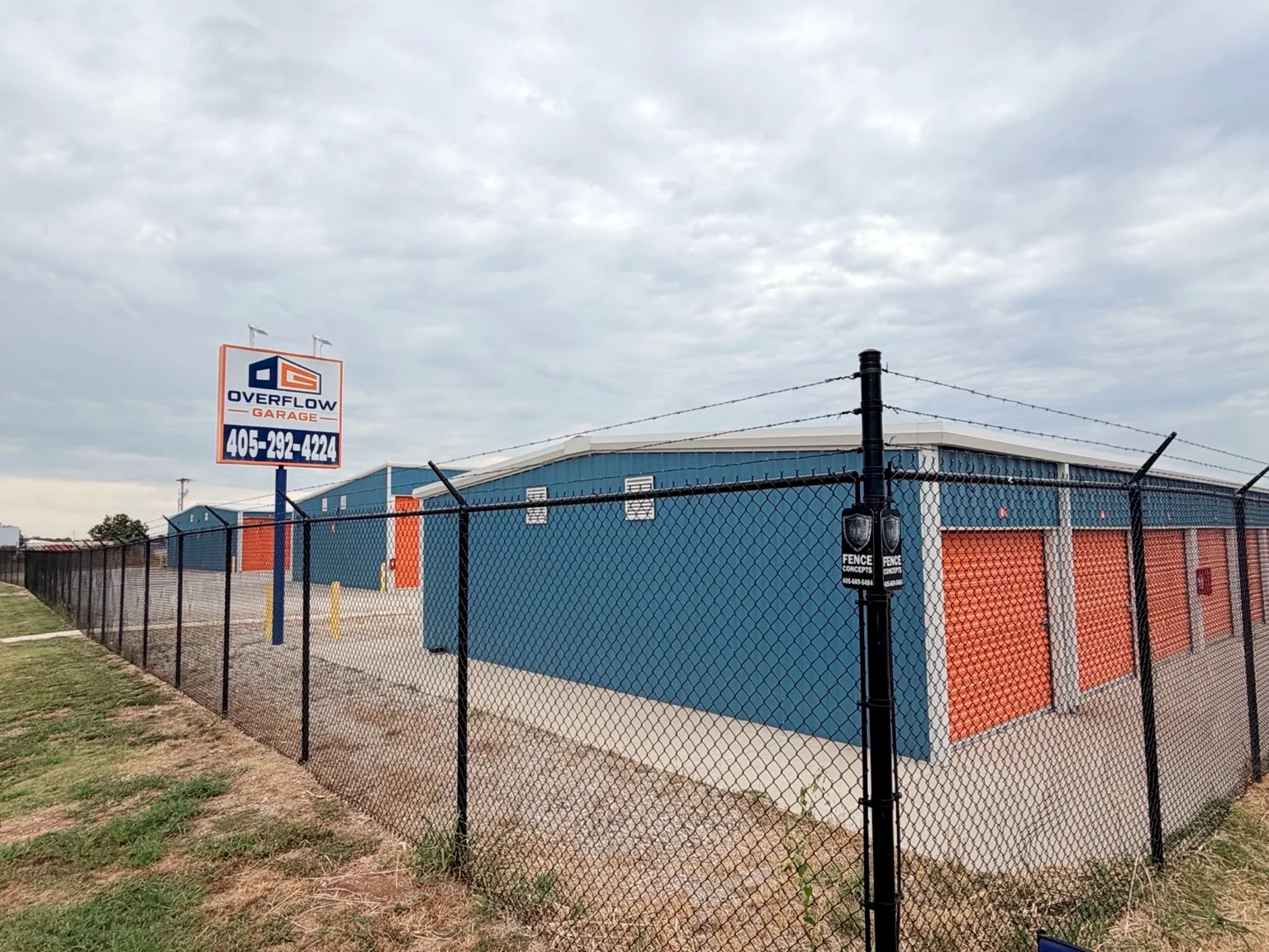 Overflow Garage sign and completed blue metal storage buildings behind perimeter fencing