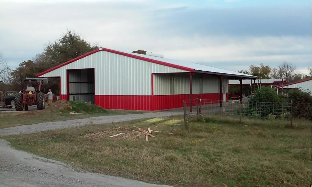 White metal building with red trim, open bays and an attached canopy