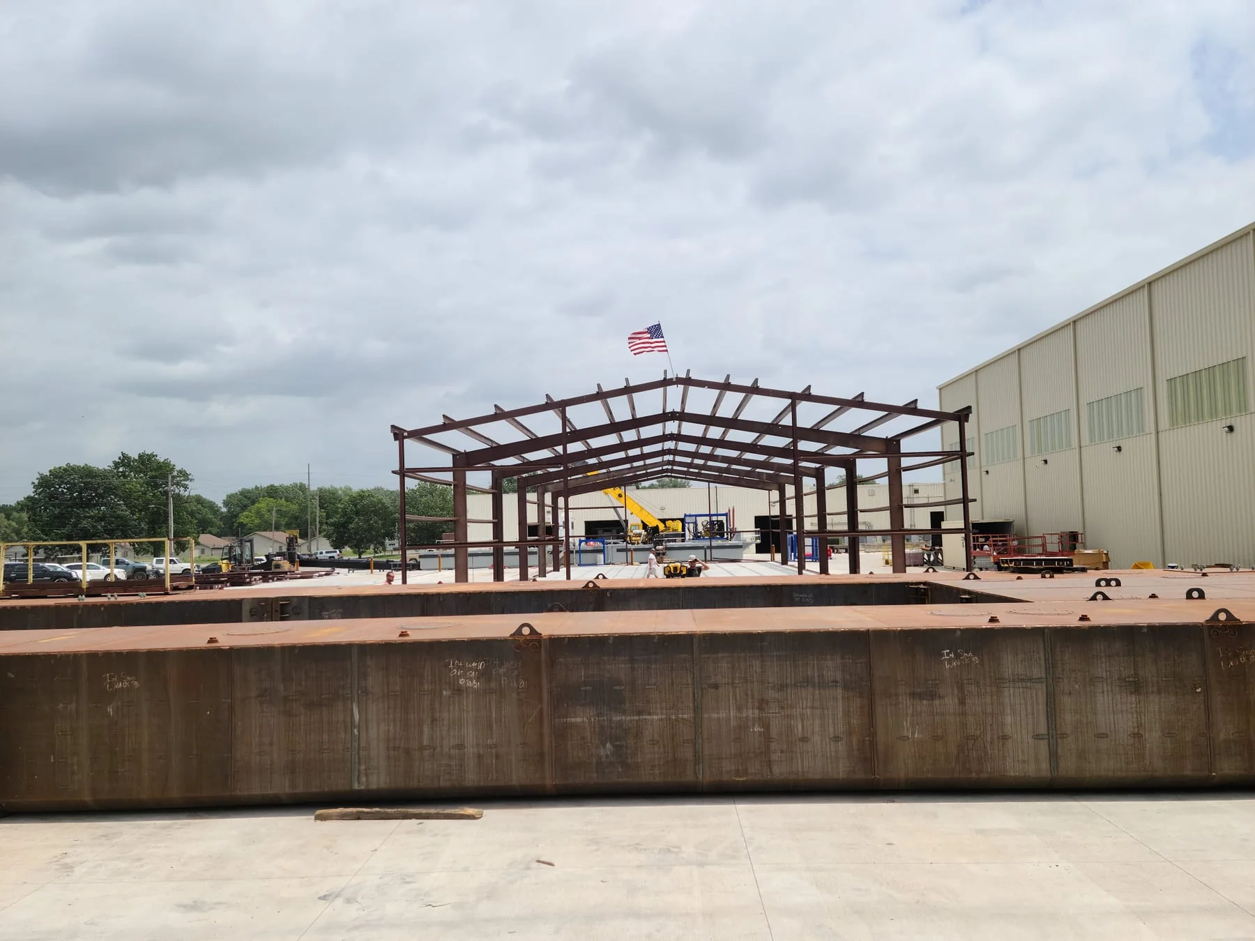 Red steel building frame with an American flag and steel beams in the foreground