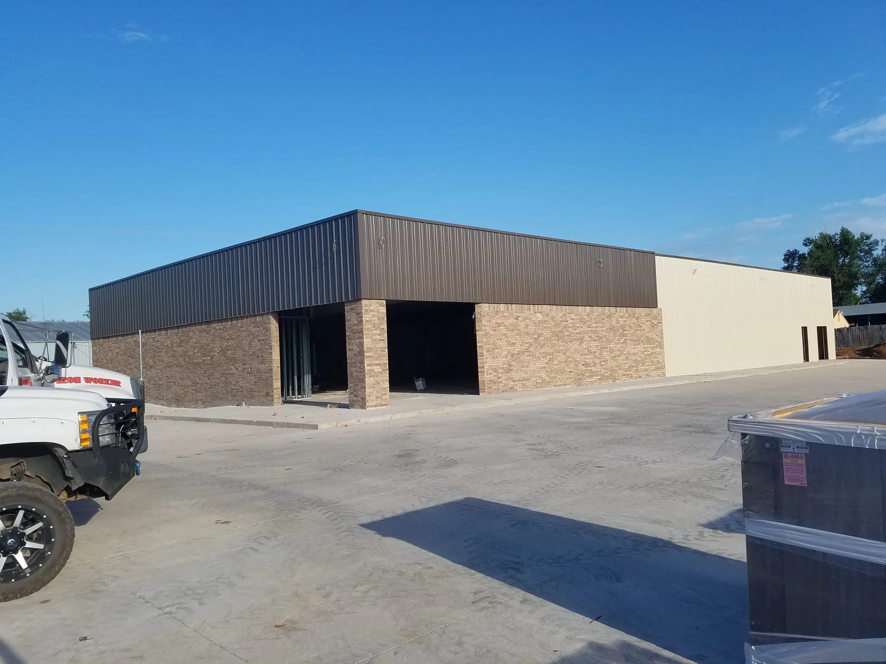 Metal-sided building with brick walls and two open entrance bays